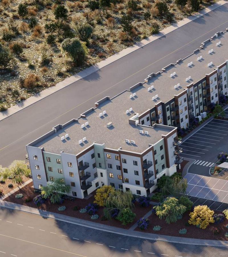 Aerial view of a modern apartment complex with solar panels and surrounding desert landscaping.